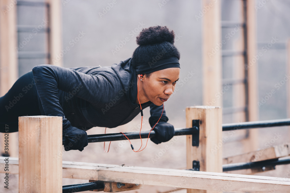 A young woman doing pushups with gloves in an outdoor environment. A young woman doing pushups with gloves in an outdoor environment.