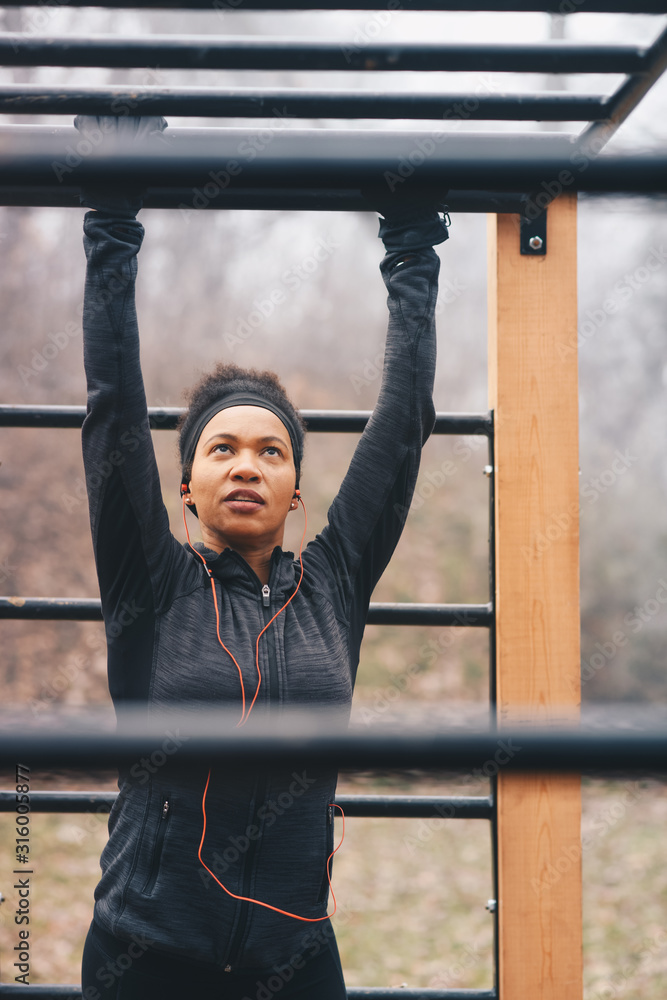Obraz premium Attractive focused african sportswoman in tracksuit doing exercises outdoors.