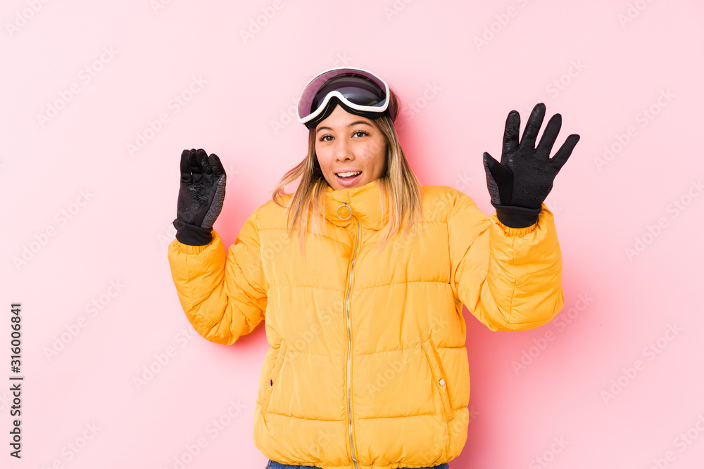Young caucasian woman wearing a ski clothes in a pink background being shocked due to an imminent danger