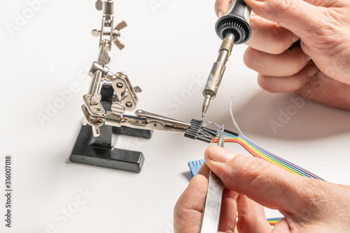 Принти на полотні technician solders cable to a plug with a soldering iron