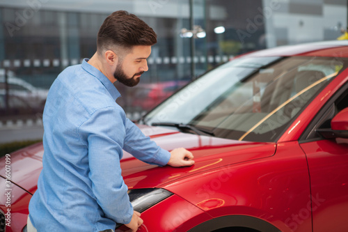 Rear view shot of a male customer examining red car at automobile dealership, copy space © mad_production
