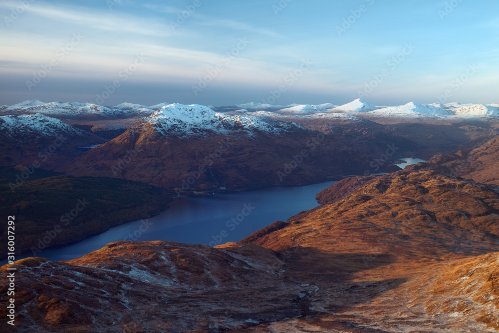 Snow covered mountain peaks and lake at sunset. Loch Lomond and The Trossachs National Park. Scotland