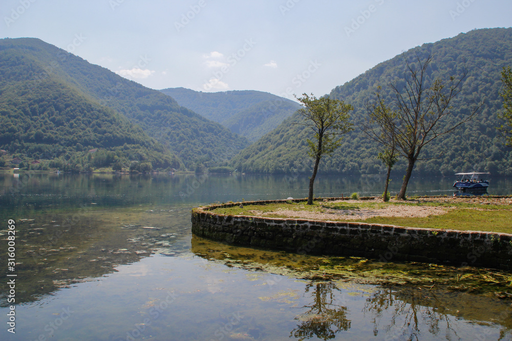 calm beautiful lake surrounded by forests and tourist boats. Sights of Bosnia and Herzegovina. calm beautiful lake surrounded by forests and tourist boats. Sights of Bosnia and Herzegovina.