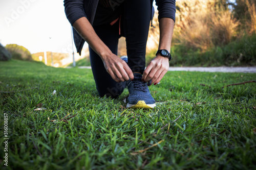 Woman tying up running shoes for a run in the park
