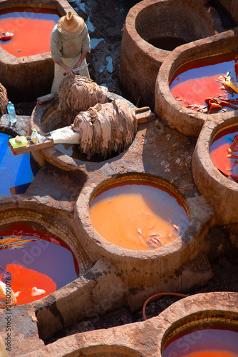 Foto Worker scrapes leather with fast movements in a traditional tannery in the city