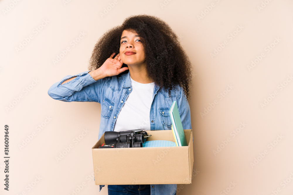 Young afro woman moving home isolated Young afro woman trying to listening a gossip. Young afro woman moving home isolated Young afro woman trying to listening a gossip.