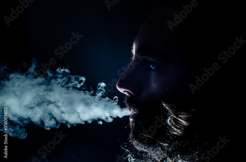 Smoking man exhaling a lot of vape smoke, with copy space.