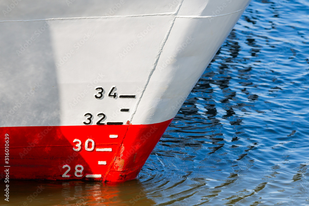 Red and white ship hull with waterline and draft scale measure