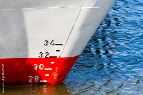 Red and white ship hull with waterline and draft scale measure photo