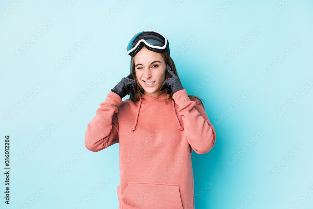 Young skier woman isolated covering ears with hands.