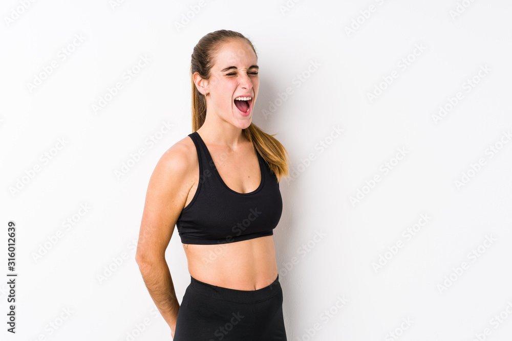 Young caucasian fitness woman posing in a white background shouting towards a copy space Young caucasian fitness woman posing in a white background shouting towards a copy space