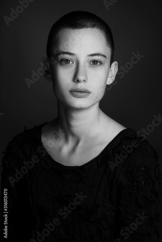 black and white portrait of fashion beautiful model, brunette girl with very short hair in studio, close up, young bold woman head shot 