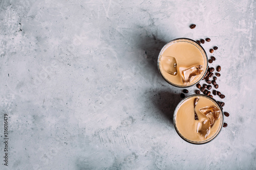 Vegan coconut milk coffee and coffee beans in two glasses on dark concrete background. photo