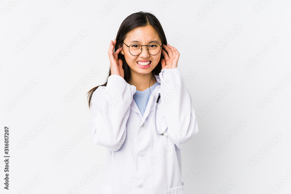 Young doctor chinese woman isolated covering ears with hands. Young doctor chinese woman isolated covering ears with hands.