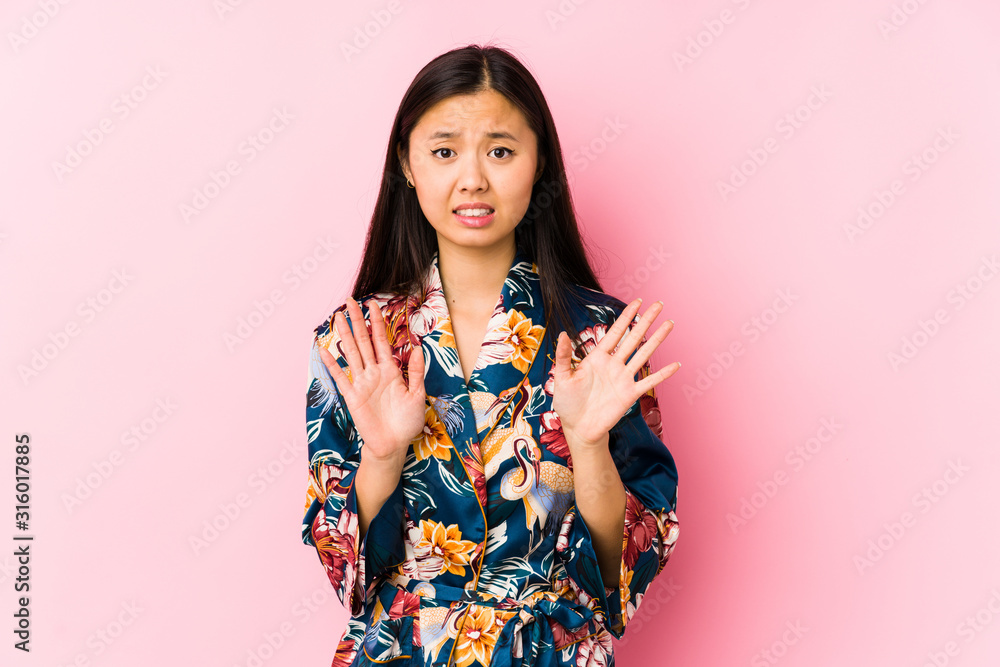 Young chinese woman wearing a kimono pajama isolated rejecting someone showing a gesture of disgust. Young chinese woman wearing a kimono pajama isolated rejecting someone showing a gesture of disgust.