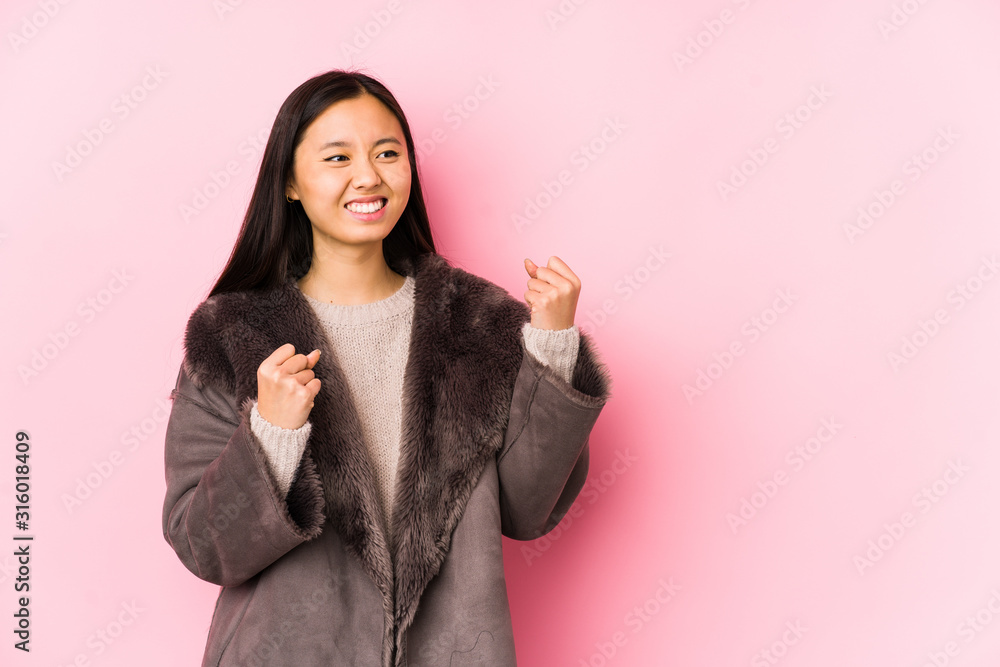 Young chinese woman wearing a coat isolated raising fist after a victory, winner concept.