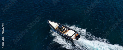 Aerial drone ultra wide top down photo of luxury rib inflatable with wooden deck cruising in deep blue open ocean sea