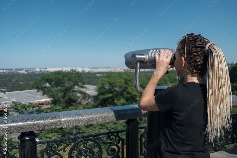young tourist looking at sightseeing observation binocular