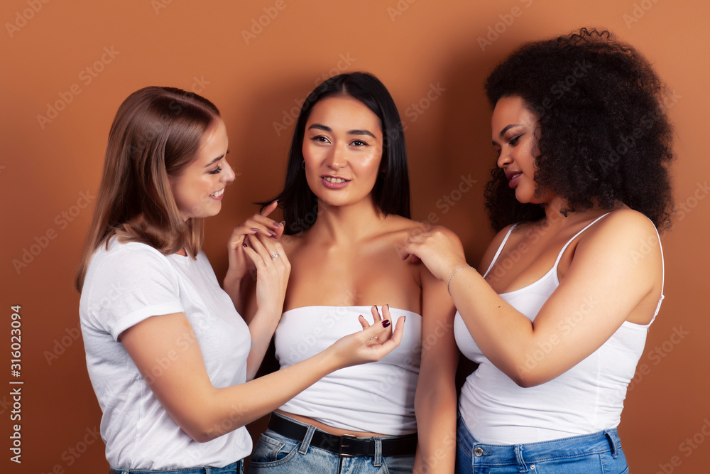 young pretty asian, caucasian, afro woman posing cheerful together on brown background, lifestyle diverse nationality people concept young pretty asian, caucasian, afro woman posing cheerful together on brown background, lifestyle diverse nationality people concept