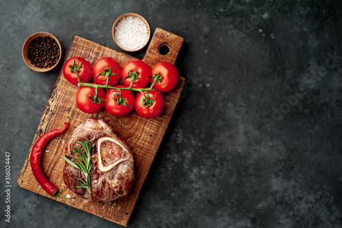 grilled steak, with tomatoes and spices on a stone background with copy space for your text
