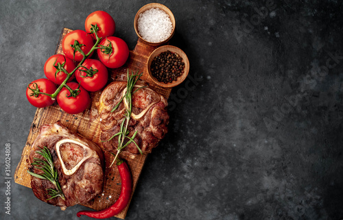 two steaks on the grill, with tomatoes and spices on a stone background, with copy space for your text. dinner concept for two