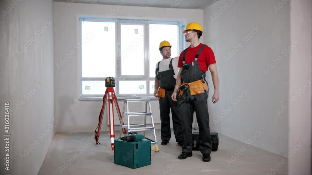Apartment repair - two men workers looking around in the draft room Apartment repair - two men workers looking around in the draft room