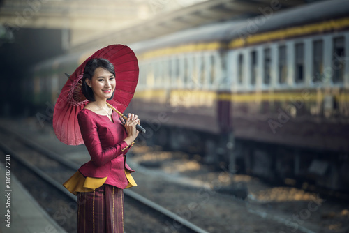Photography Traveler Asia girl wear traditional dress with umbrella waits for train on railw