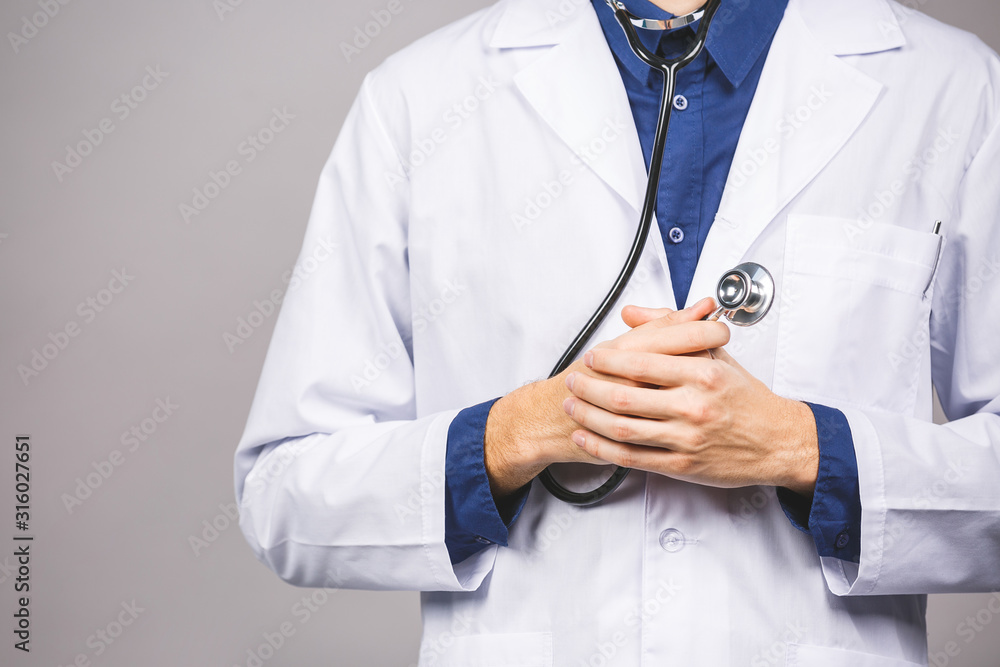 Handsome young medic doctor holding a stethoscope, isolated over grey background. Handsome young medic doctor holding a stethoscope, isolated over grey background.