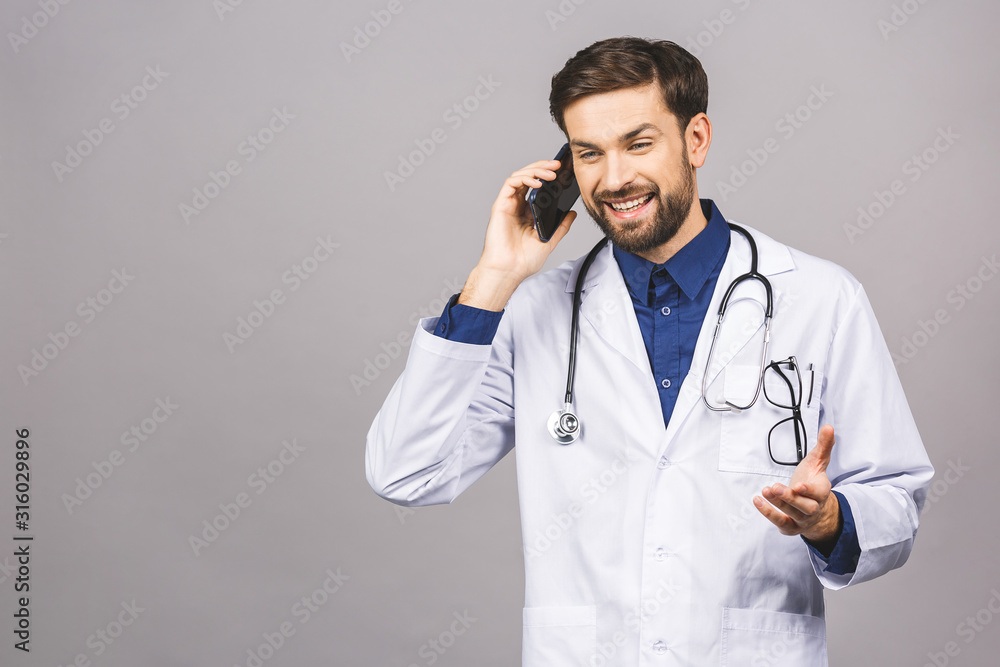 Close up shot of handsome man doctor isolated on grey background talking on smartphone, smiling positively Close up shot of handsome man doctor isolated on grey background talking on smartphone, smiling positively