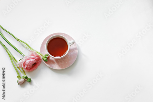 Overhead view of cup of tea and pink flowers isolated on white background. Flat lay, romantic female morning.