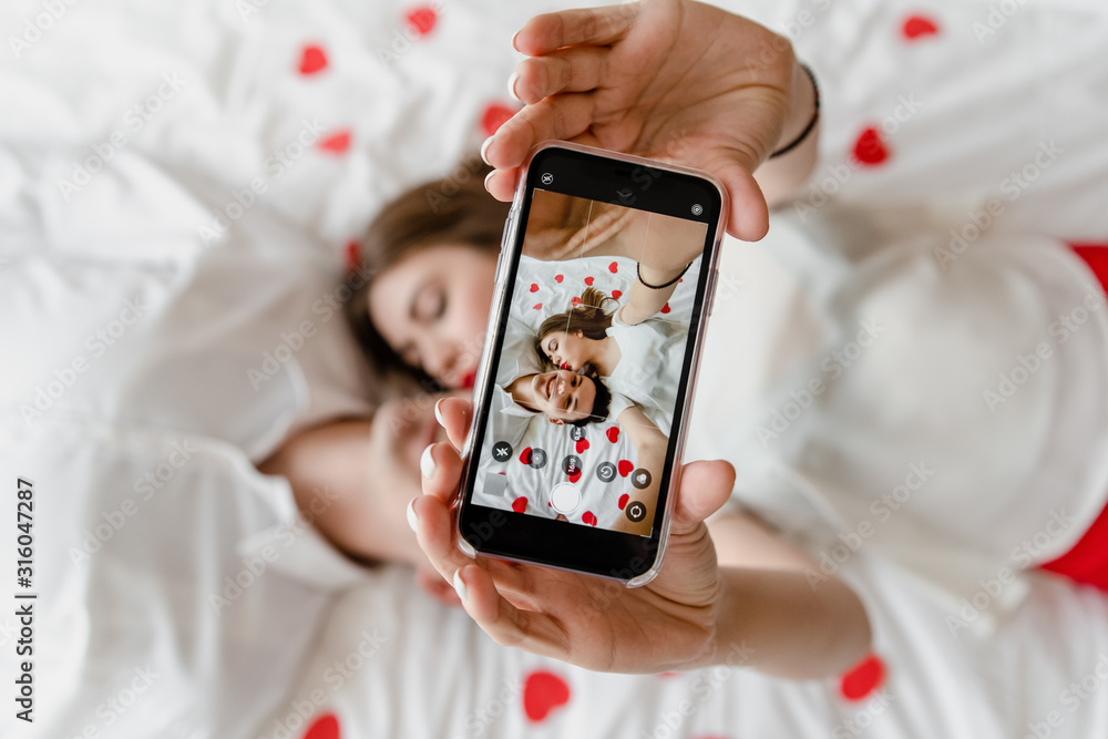phone screen with selfie of man and woman in love in bed kissing