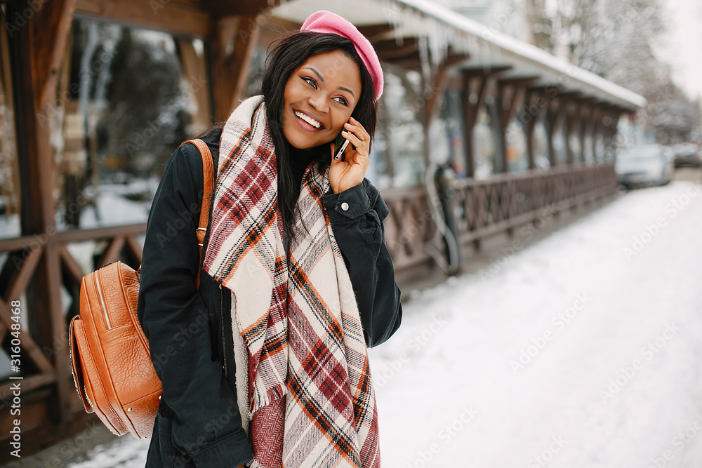Fototapeta premium Cute black woman have fun in a city. Beautiful black girl in a pink beret.