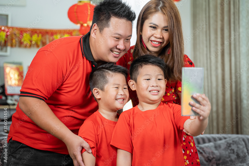 Asian chinese family with two son smiling holding cell phone to take selfie with father and mother.Asian Chinese family celebrates Lunar New Year Asian chinese family with two son smiling holding cell phone to take selfie with father and mother.Asian Chinese family celebrates Lunar New Year
