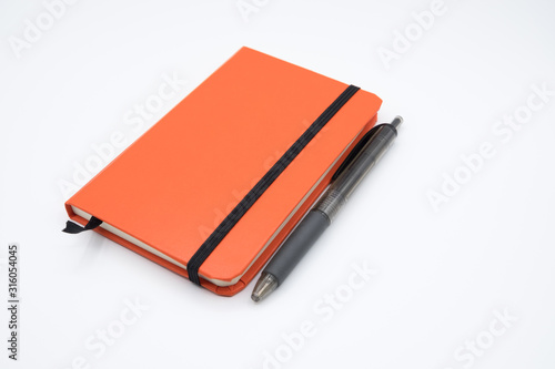 Orange notebook with pen on white background