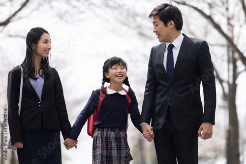 桜並木の下を歩く家族