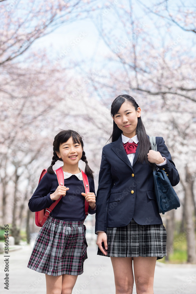 桜並木の下に立つ姉妹