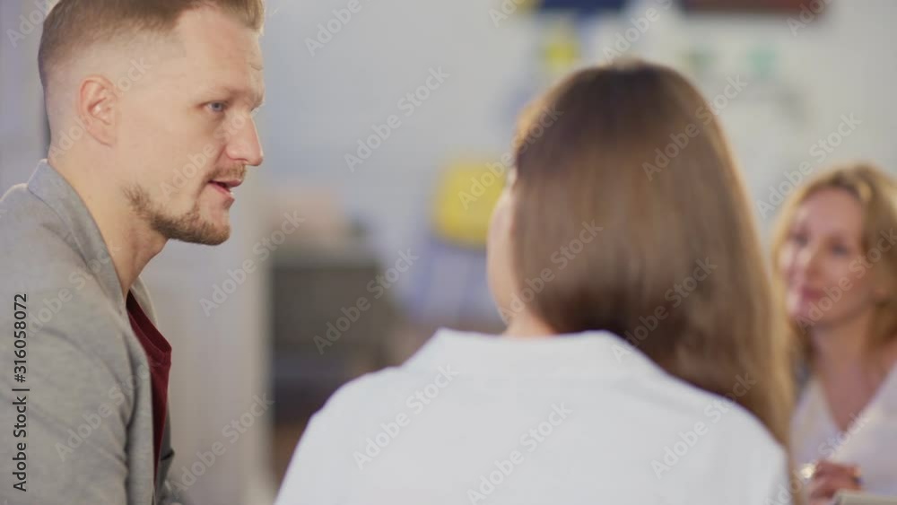 Tracking left shot of young married couple discussing relationship problems during appointment with defocused female family psychologist Tracking left shot of young married couple discussing relationship problems during appointment with defocused female family psychologist