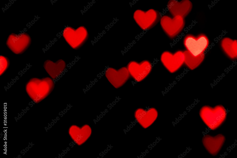 Black background with bright red warm heart shaped bokeh lights. Holiday, Valentines Day background. Ideal to layer with any design. Horizontal