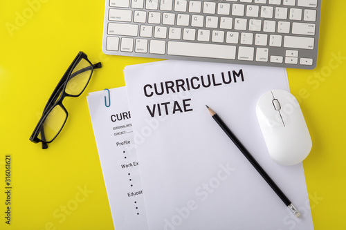 CV, curriculum vitae with computer keyboard, mouse, pencil on yellow desk, top view photo