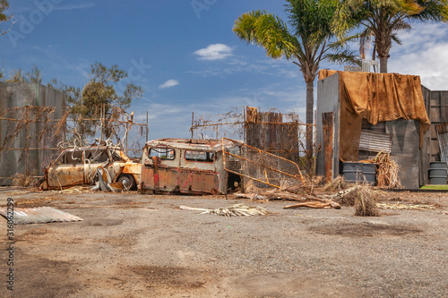 rusty car and truck next to a metal fence in a junkyard photo