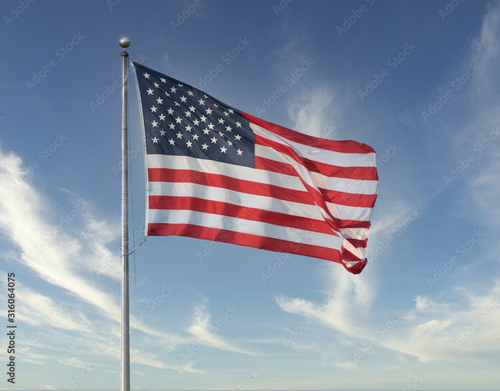 American flag flies high on a windy day with blue skies American flag flies high on a windy day with blue skies