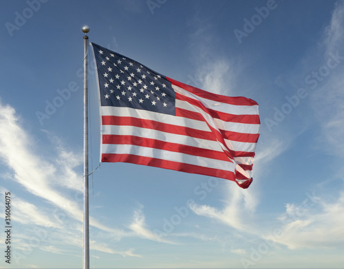 American flag flies high on a windy day with blue skies