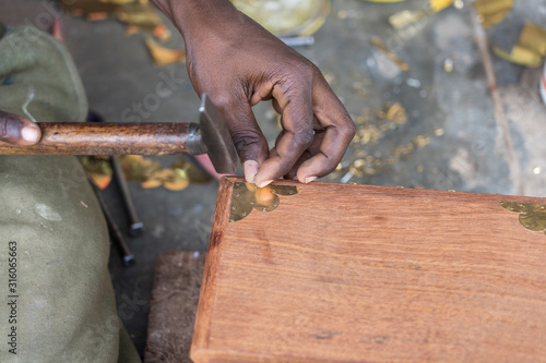 African man hammer a nail into a wooden box on the street on the island of Zanzibar, Tanzania, Africa, close up
