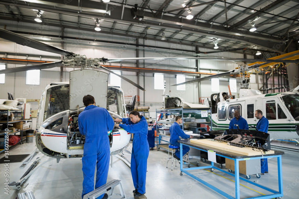 Mechanics repairing helicopter engine in airplane hangar Stock Photo
