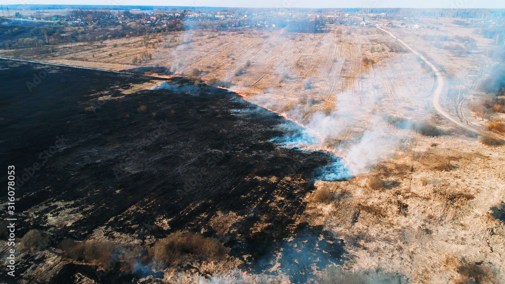 Large burnt field covered in black soot. Fire spreads in several places. Great smoke from burning places. Large burnt field covered in black soot. Fire spreads in several places. Great smoke from burning places.