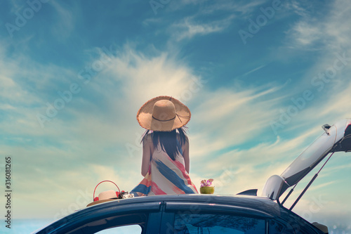 woman sitting on the car roof cheerfully with enjoy fresh coconut fruit in hand, summer and vacation on the sea beach
