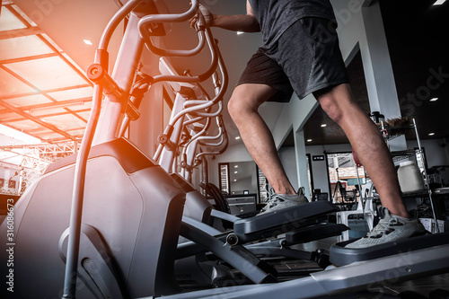 Young man working out on an elliptical trainer in gym photo