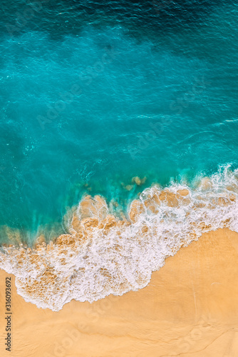 Beautiful sandy beach with turquoise sea, vertical view. Drone view of tropical turquoise ocean beach Nusa penida Bali Indonesia. Lonely sandy beach with beautiful waves. Beaches of Indonesia.