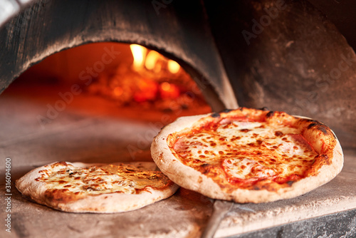 Photos Baked tasty margherita pizza in Traditional wood oven in Naples restaurant, Italy