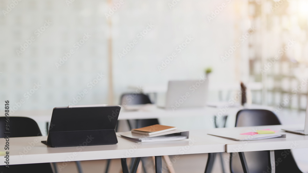 Cropped shot of office room with digital tablet and office supplies on white desk with blurred Cropped shot of office room with digital tablet and office supplies on white desk with blurred